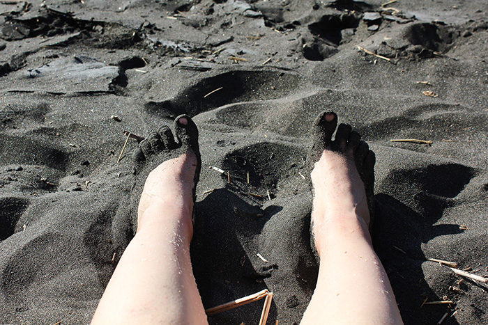 Meine Füße in schwarzem Sand